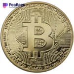 Eine physische Bitcoin-Münze, auf deren Oberfläche das Wort "peakeen" prominent abgebildet ist.