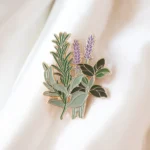 Eine detaillierte Emaille-Anstecknadel mit einer Vielzahl von Kräutern, die ihre natürliche Schönheit und leuchtenden Farben hervorheben.