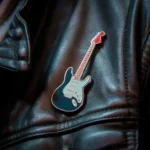 Eine schwarze Punkrock-Gitarren-Anstecknadel, die an einer Lederjacke befestigt ist und einen mutigen und kantigen Stil zeigt.