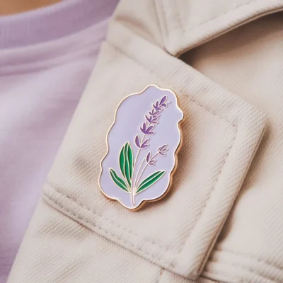 Un elegante alfiler de color lavanda adornado con una vibrante flor morada, ideal como accesorio para ropa o bolsos.