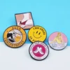 Eine Kollektion von vier Anstecknadeln mit jeweils unterschiedlichen Designs, darunter eine Anstecknadel mit dem Firmenlogo.